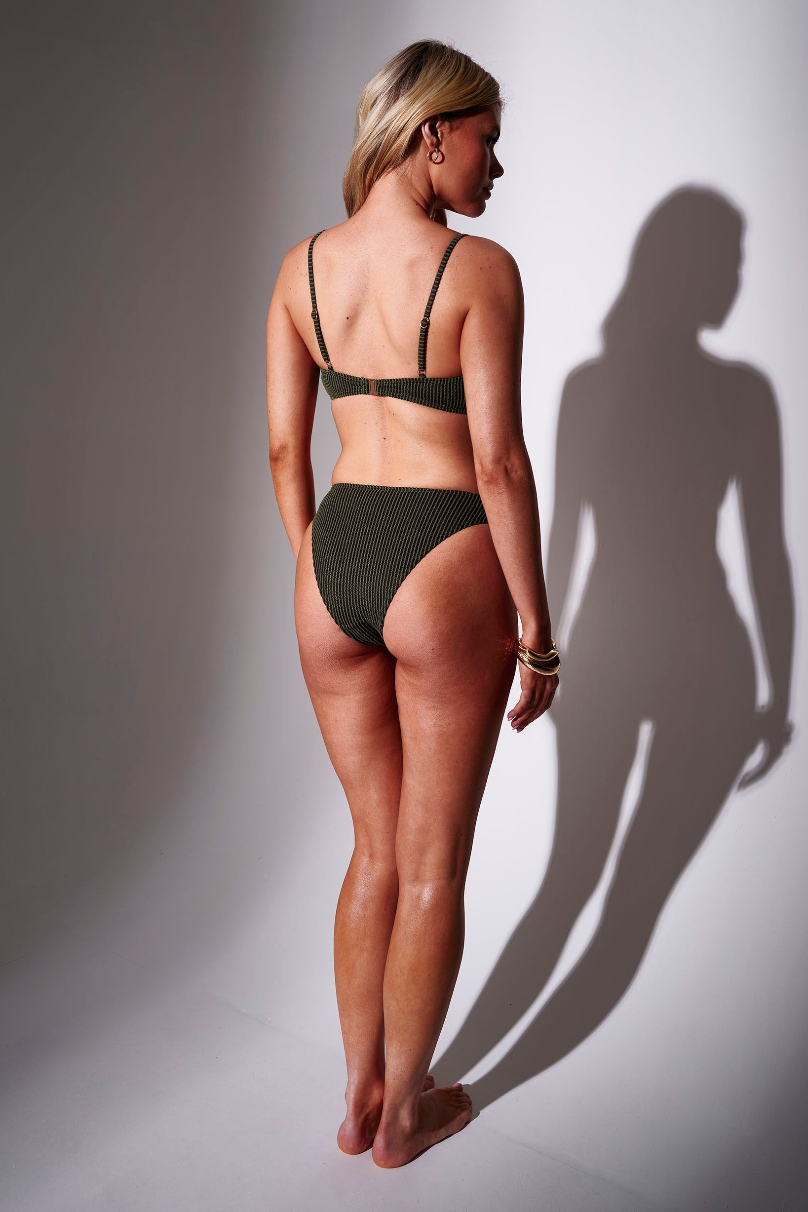 Woman wearing a khaki green crinkle fabric bikini against a white background