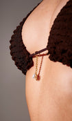 Model wearing brown frilly triangle bikini top with gold decal – close-up view on plain background