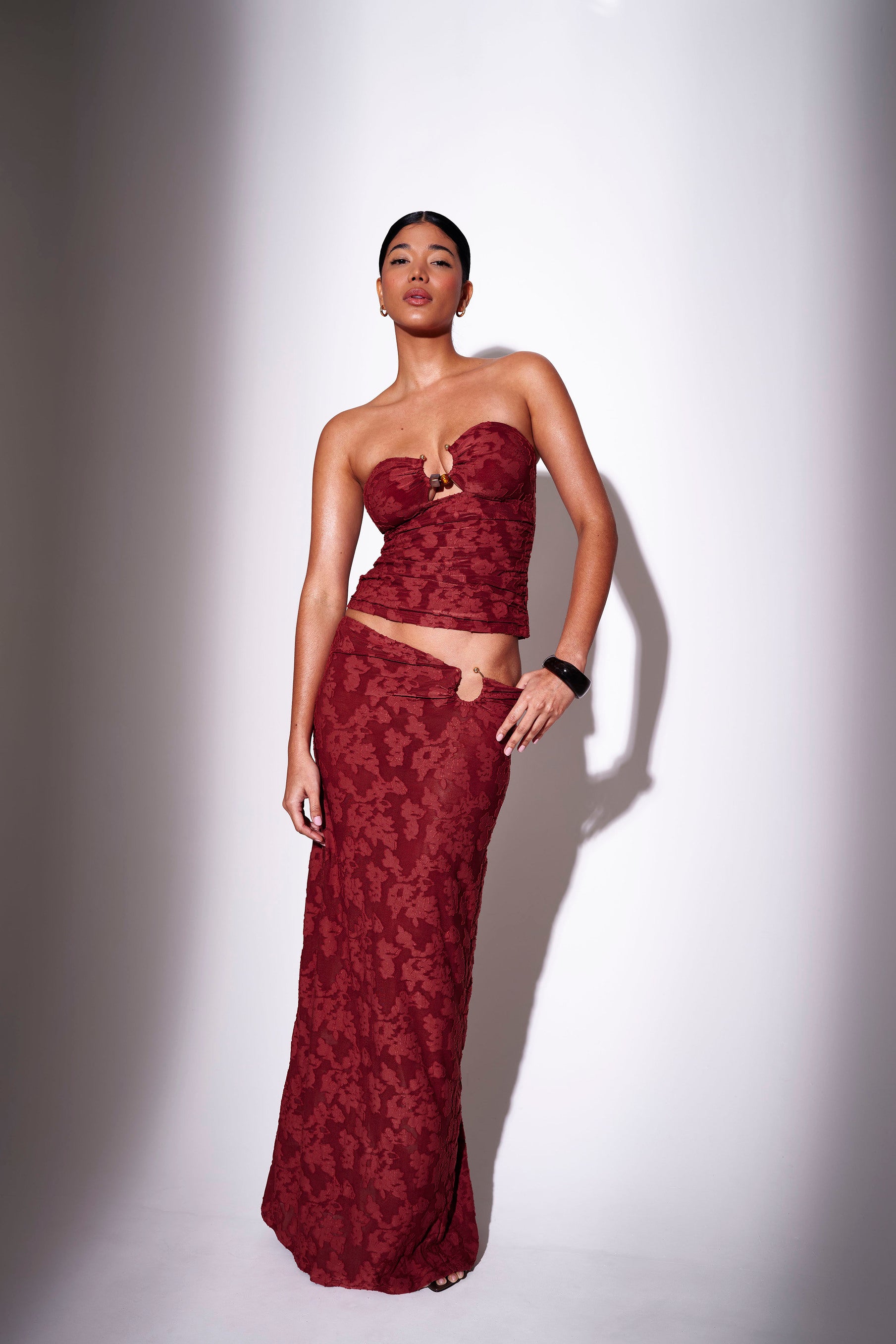 Model wearing a burgundy floral print bandeau top with matching maxi skirt - front view on plain background