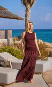 Woman in a brown shirred maxi skirt with matching top standing by a pool with ocean view