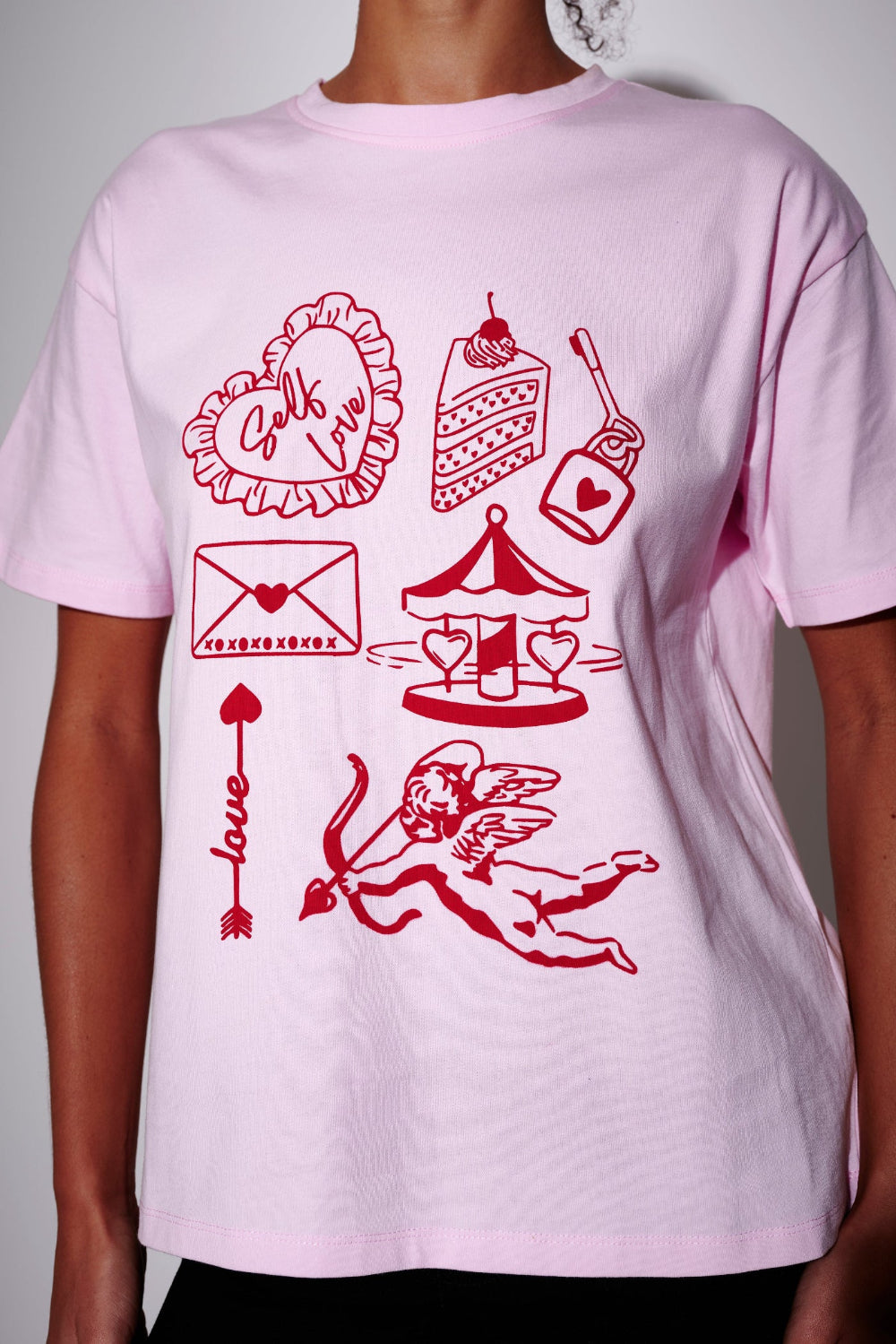Light pink oversized t-shirt with red self-love graphics and text on a plain background