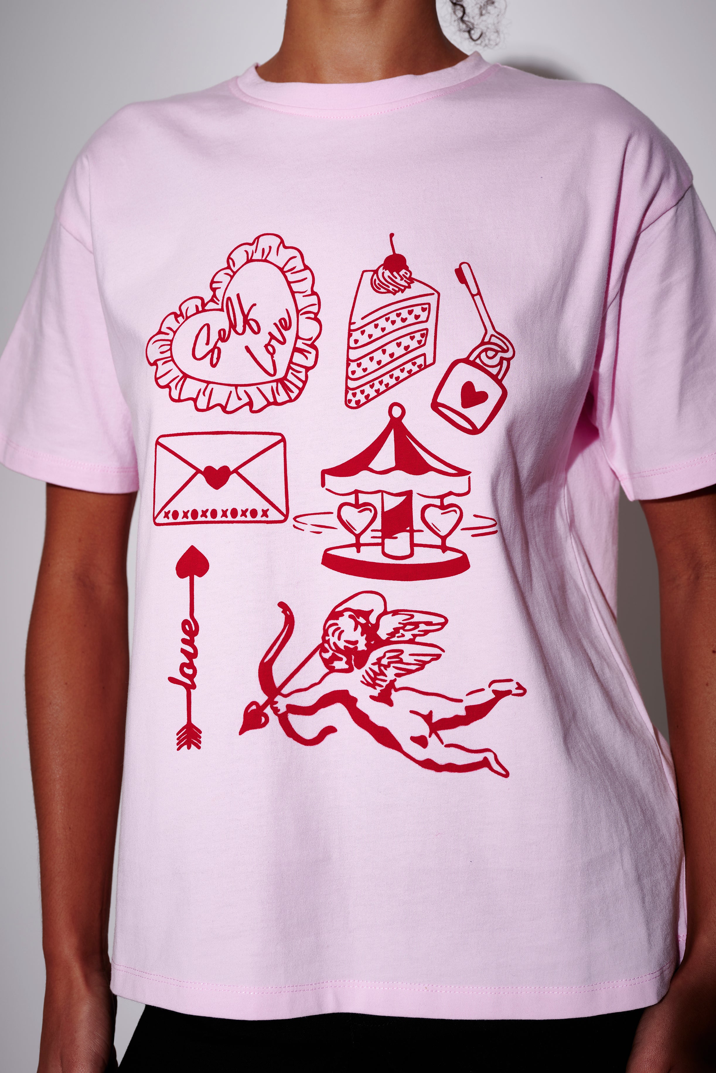 Light pink oversized t-shirt with red self-love graphics and text on a plain background