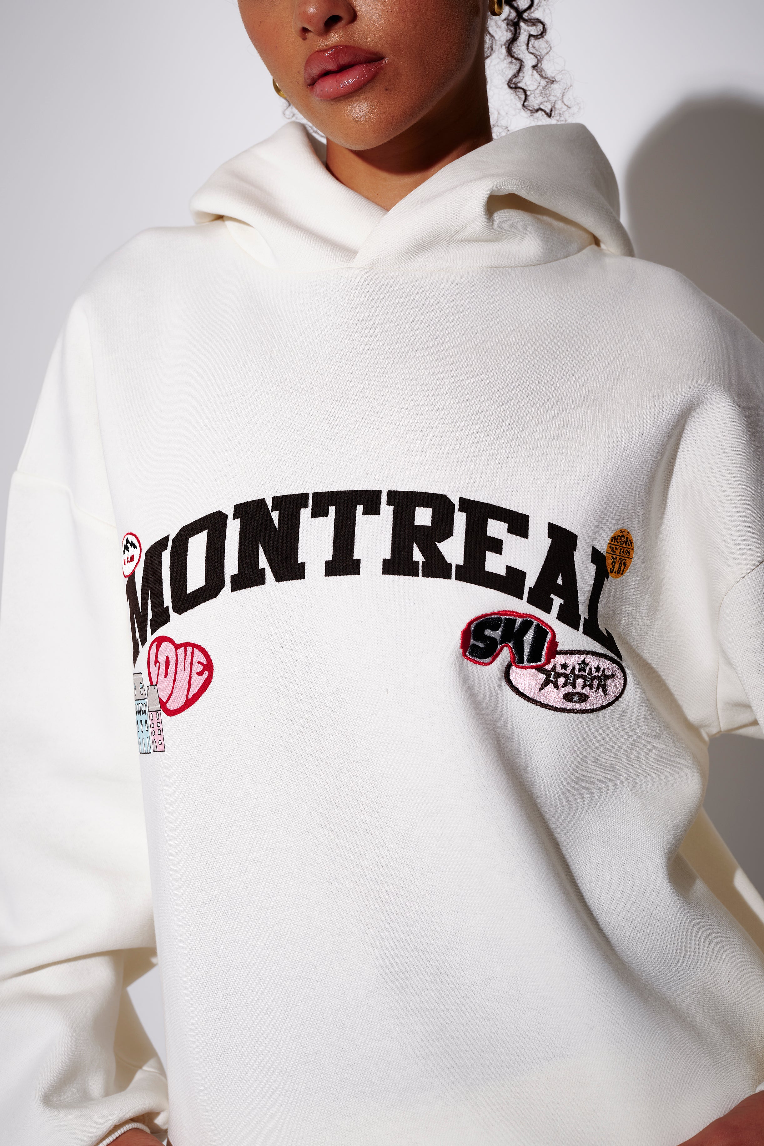 Model wearing a cream oversized hoodie with 'Montreal' graphic text - front view on plain background
