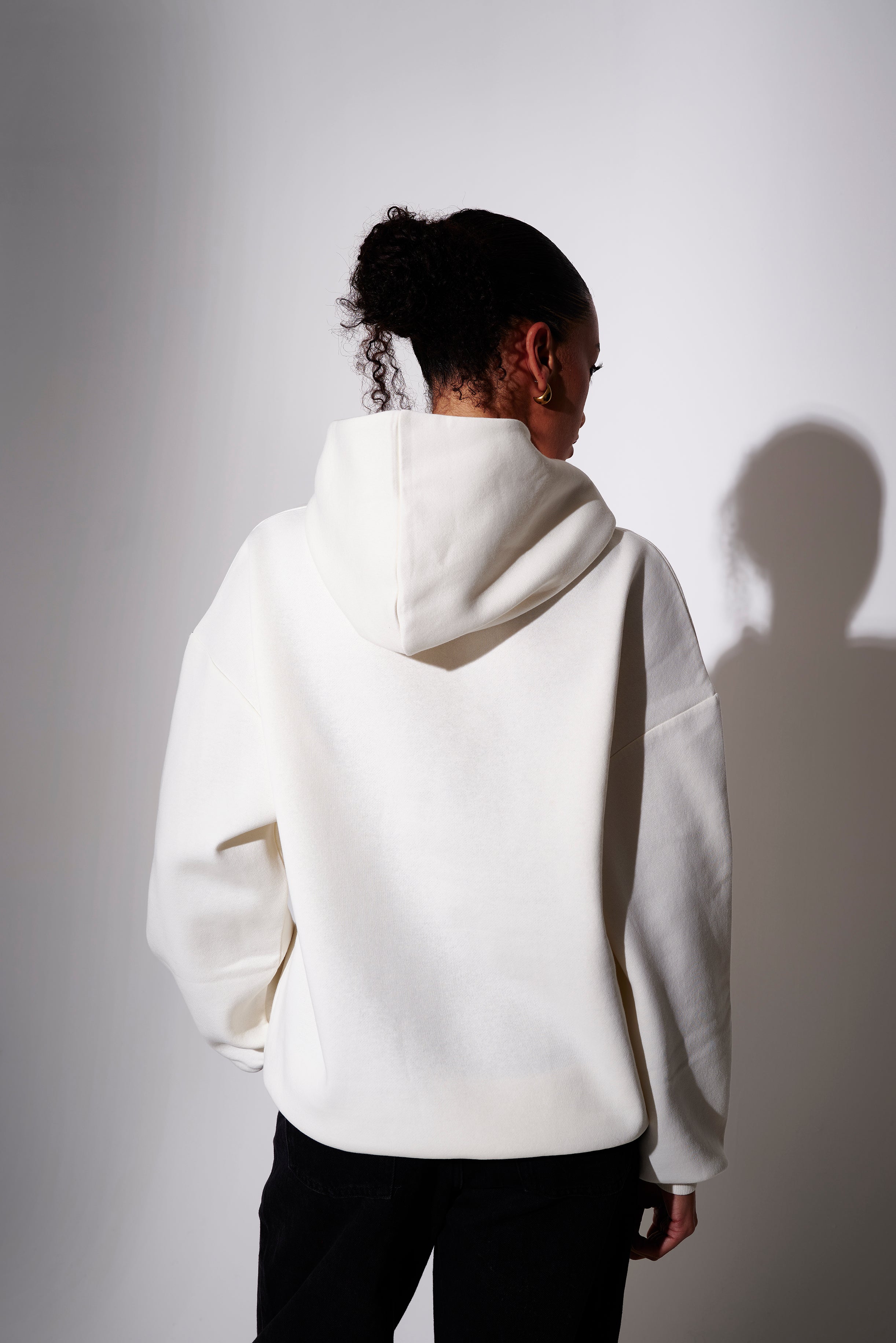 Model wearing a cream oversized  hoodie  - back view on plain background