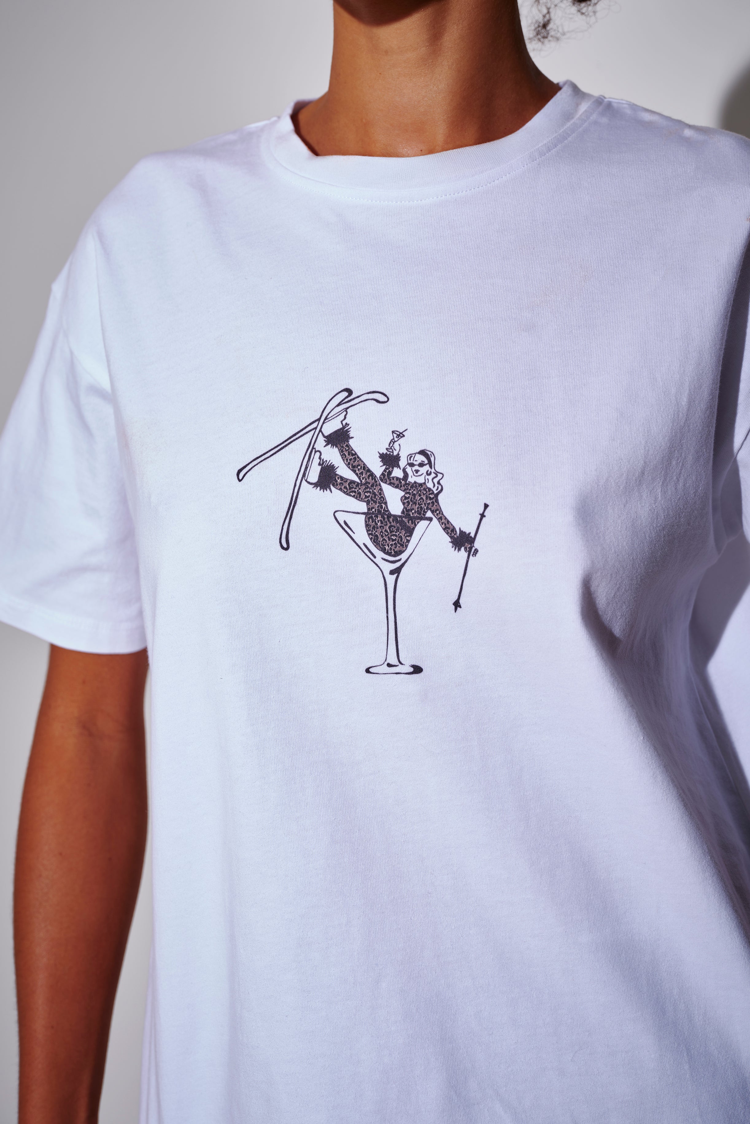 Model wearing a white t-shirt with a skier in cocktail glass artwork - close-up front view on a plain background