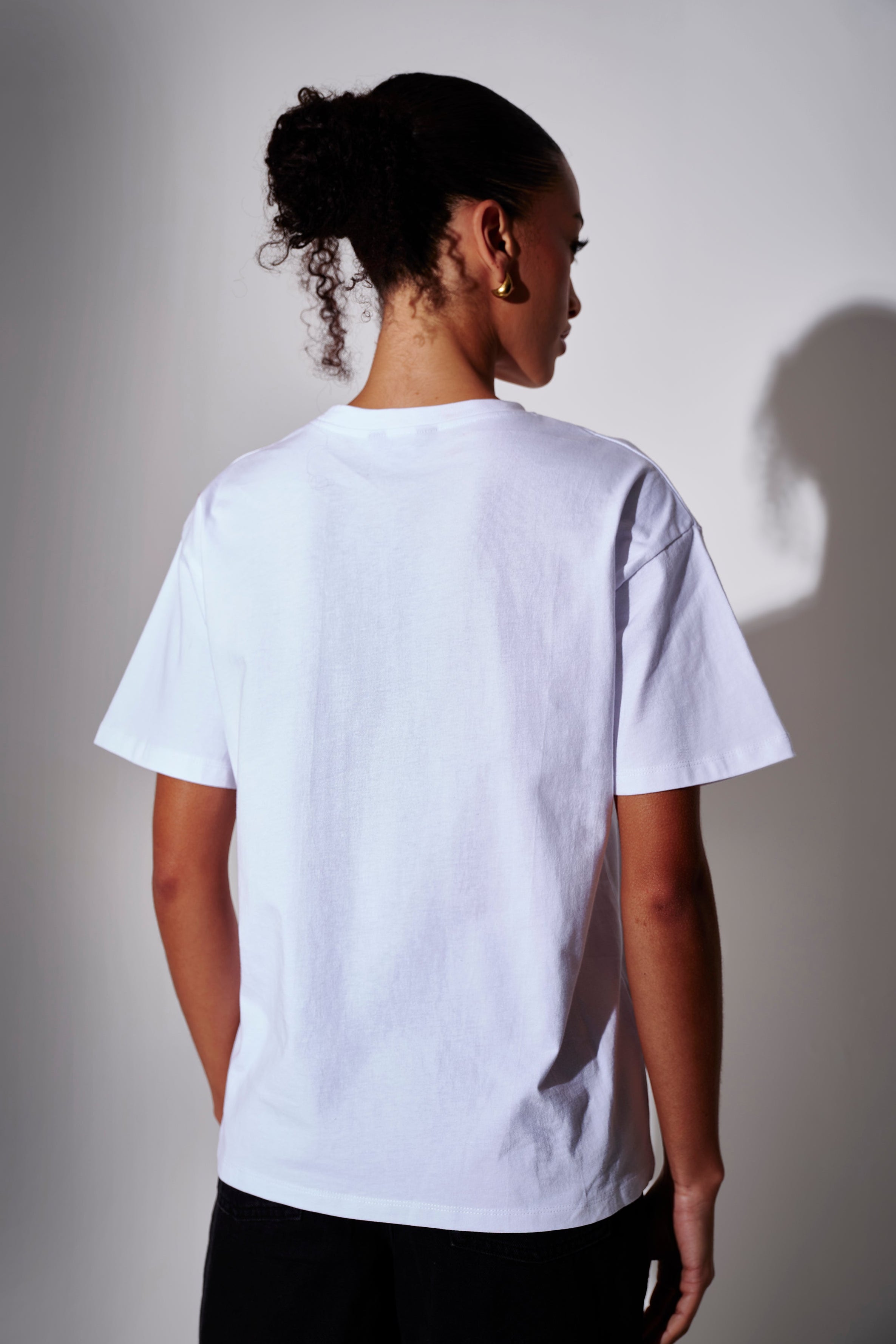 Model wearing a white oversized t-shirt - back view on a plain background