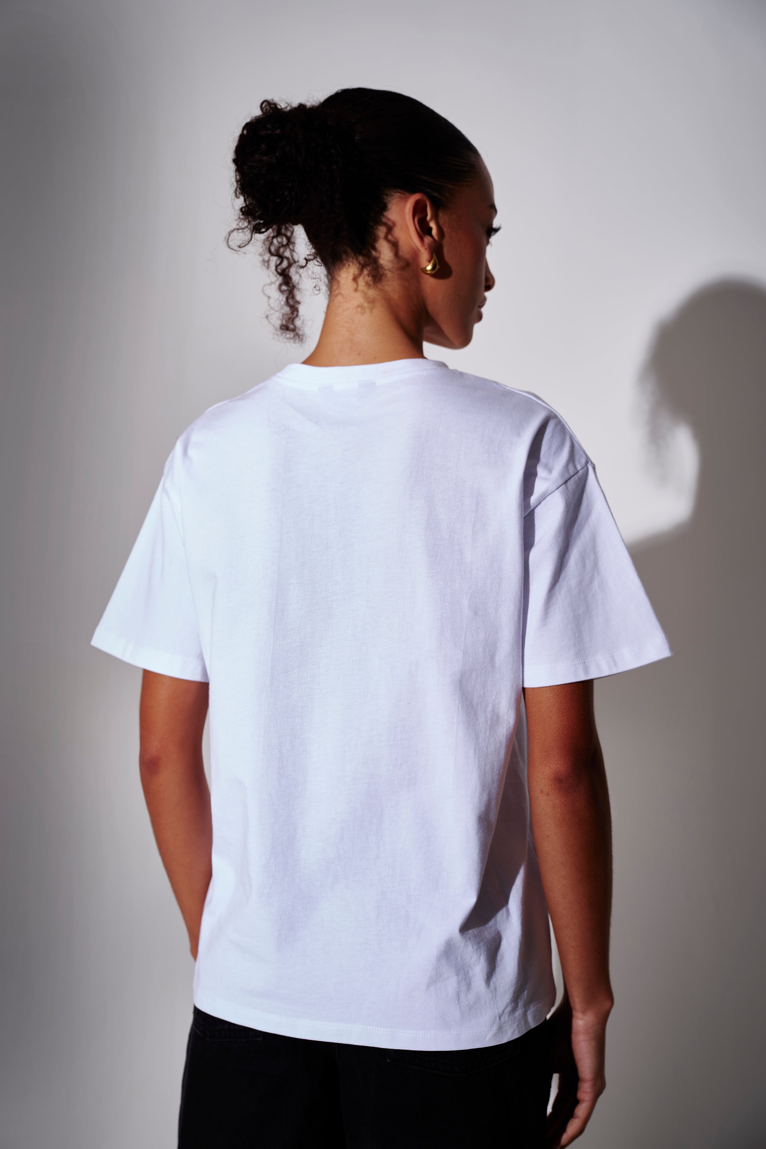 Model wearing a white oversized t-shirt - back view on a plain background