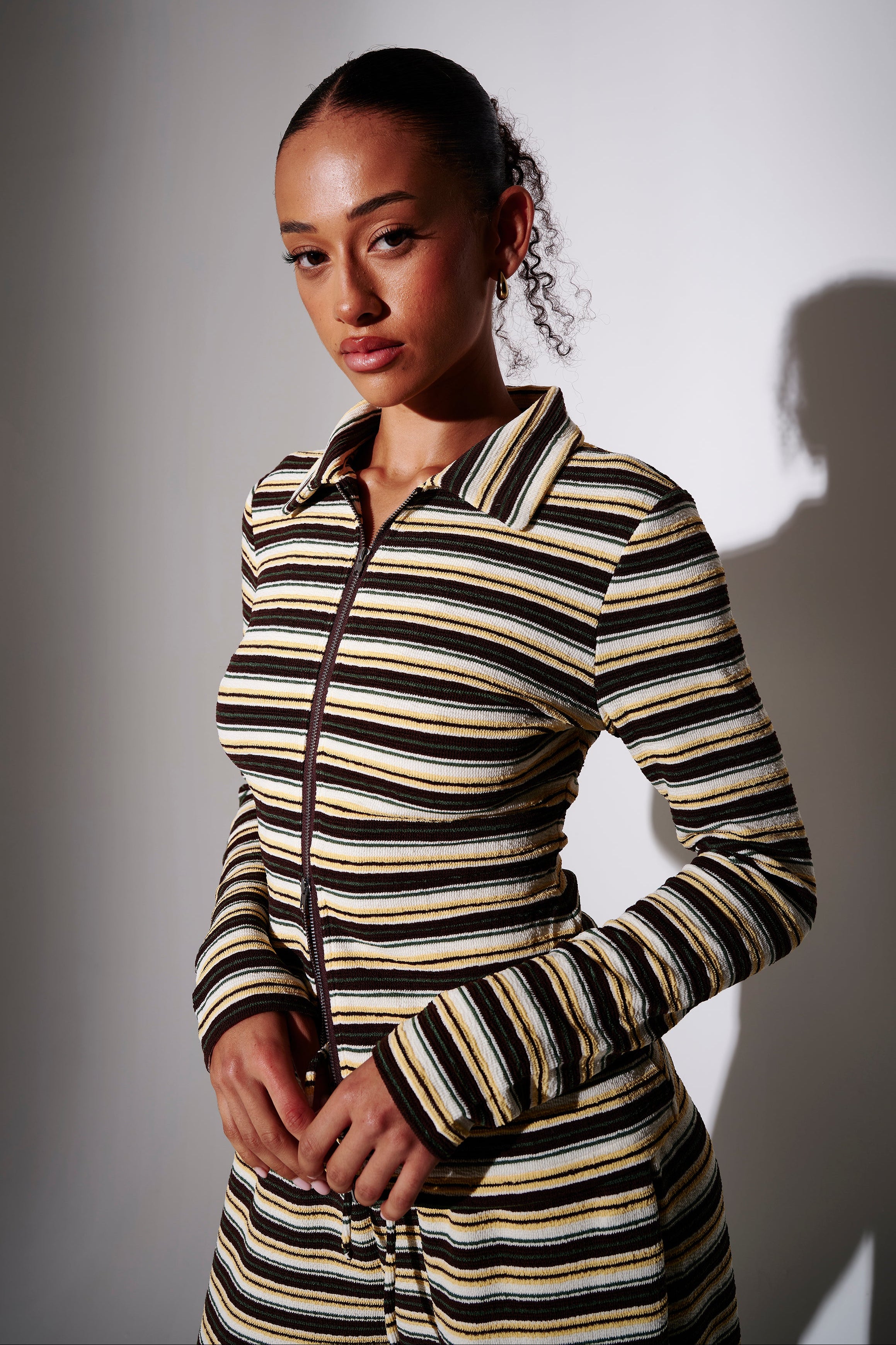 Model wearing a black and yellow striped zip-up long sleeve shirt - front view on plain background