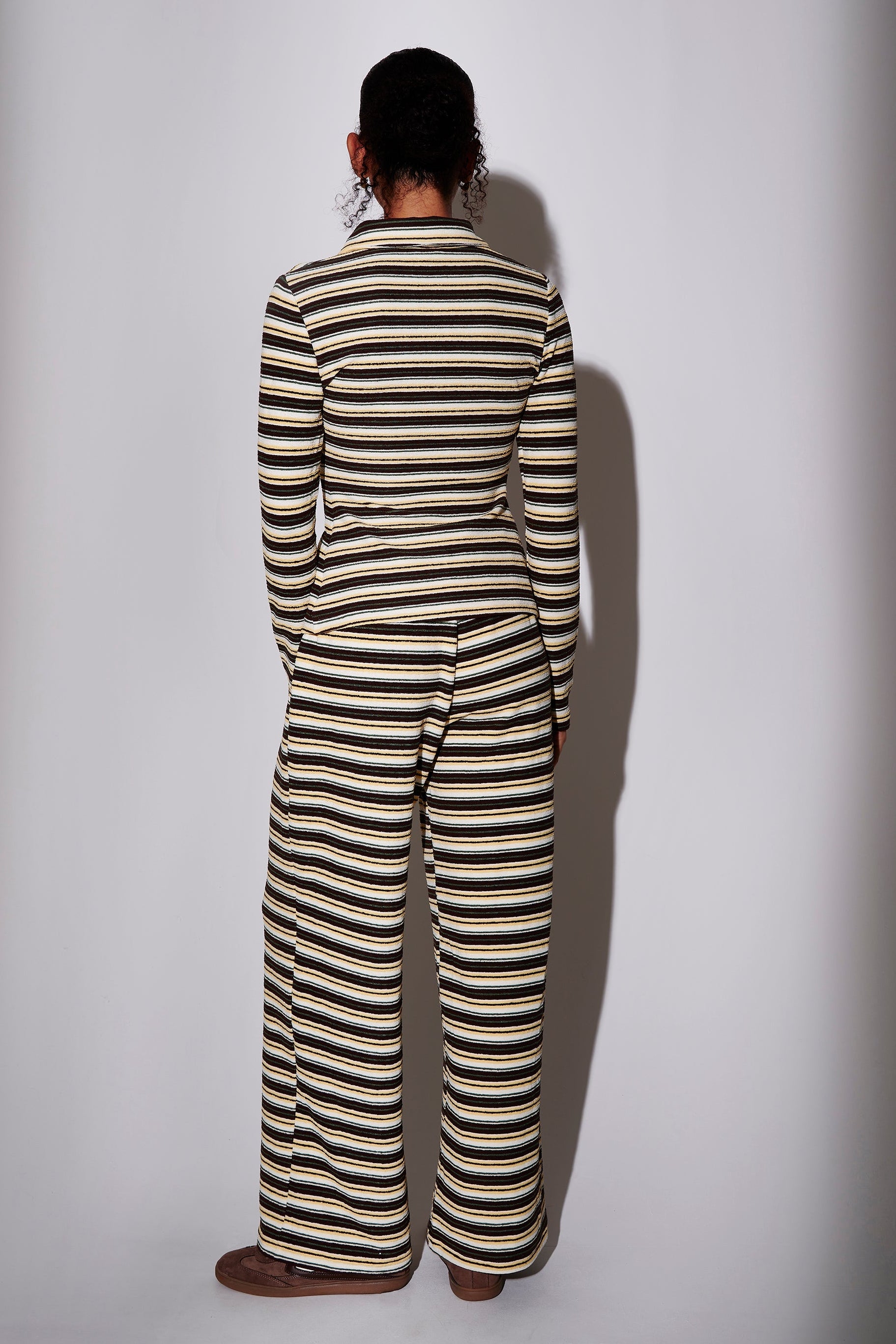 Model wearing a black and yellow striped long sleeve shirt with matching trousers - back view on plain background
